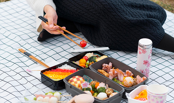 A Person eating with four plastic bento boxes