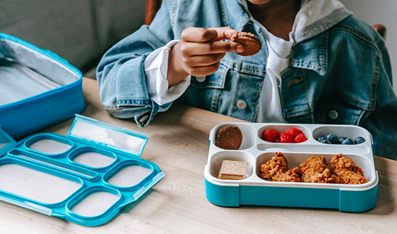 Boy in denim eating tasty breakfast in plastic container