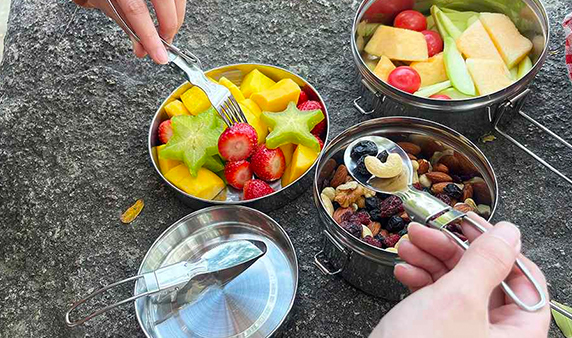Person using stainless Steel bento box with fruits